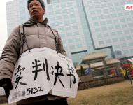2006年1月24日，在京從事降水井工程的老陳掛著寫有“賣判決書”的紙口袋在北京站口附近來(lái)回走著。曾是名小工頭的老陳被欠工程款4萬(wàn)元，為了給工人們開資不得已賣掉了打井機(jī)器。2002年法院宣判老陳勝訴，可四年后該判決仍得不到執(zhí)行，無(wú)奈之中老陳只好上演此幕。程寧/視覺(jué)中國(guó)